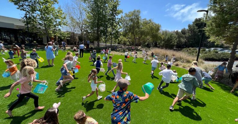 A lively scene of children participating in an Easter egg hunt on a sunny day.